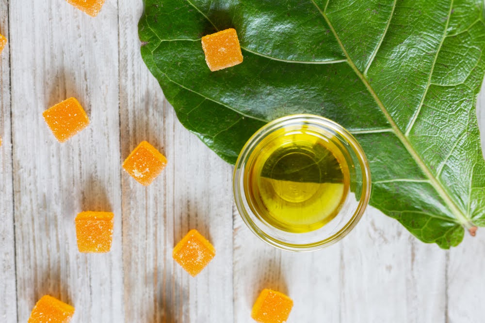 birdseye view of cbd gummies and oil on a light wooden counter