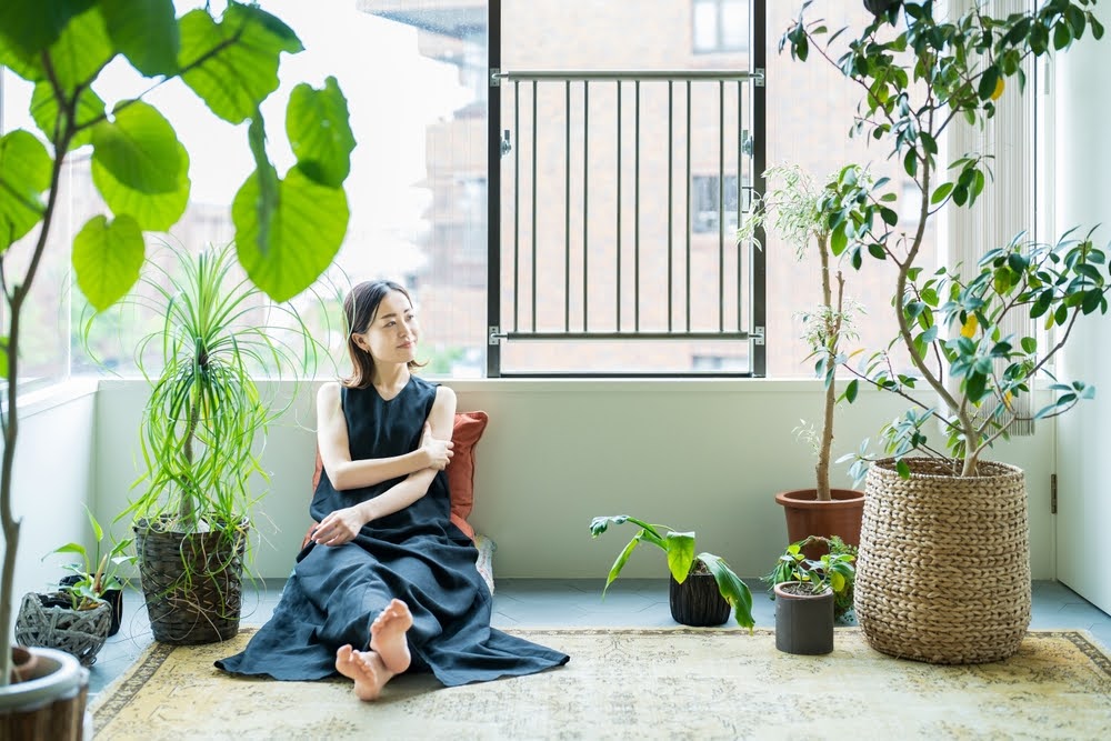 woman sitting among plants in a sun room balcony