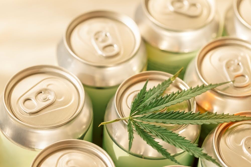 beverage cans lined up with a cannabis leaf spread out over the top of some of them