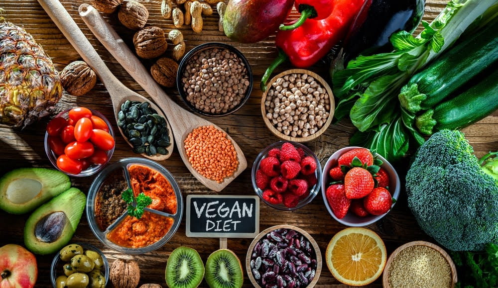 vegetable and fruit spread with a small chalkboard in the middle that says "vegan diet”