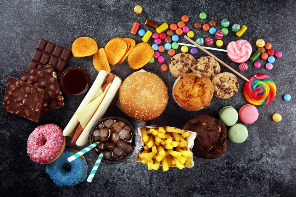 overhead view of fast food, candy and sweets on a black counter