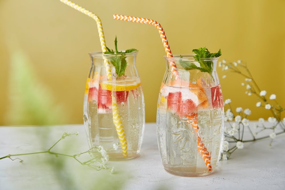 seltzers with sliced grapefruit, lemon and basil on a white counter