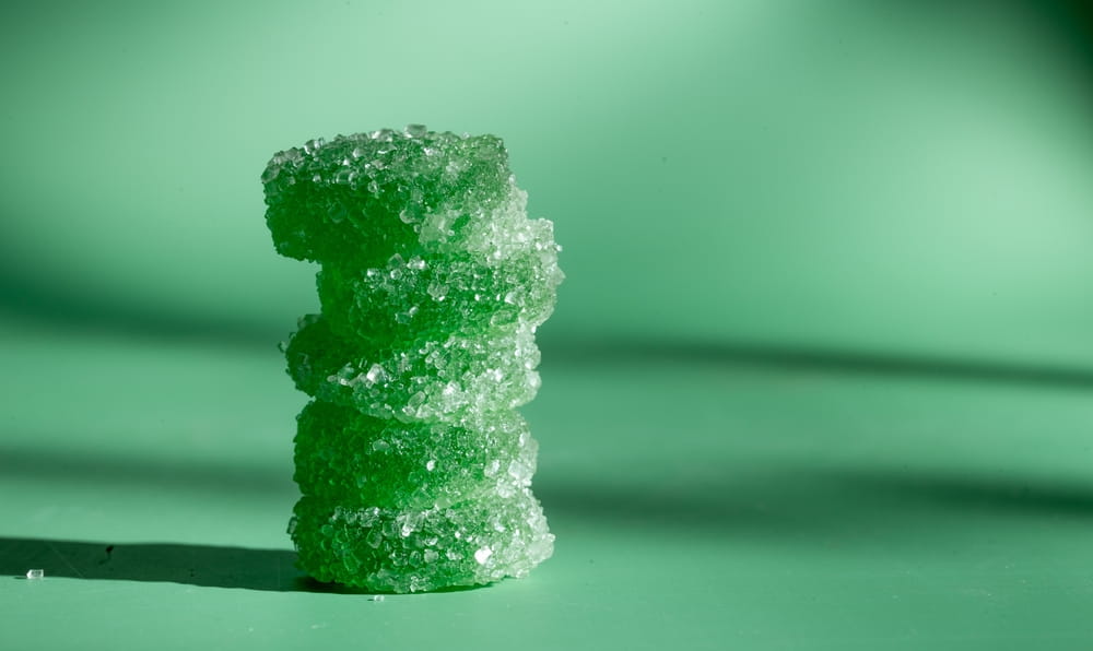 stack of round, flat green gummies on a green background