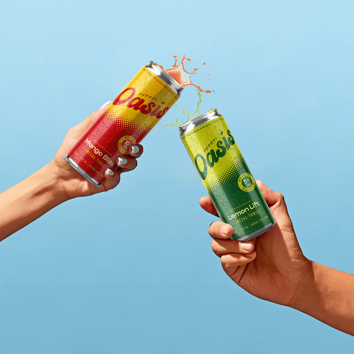 two hands holding up lemon and mango cans of Herbal Oasis against a blue backdrop