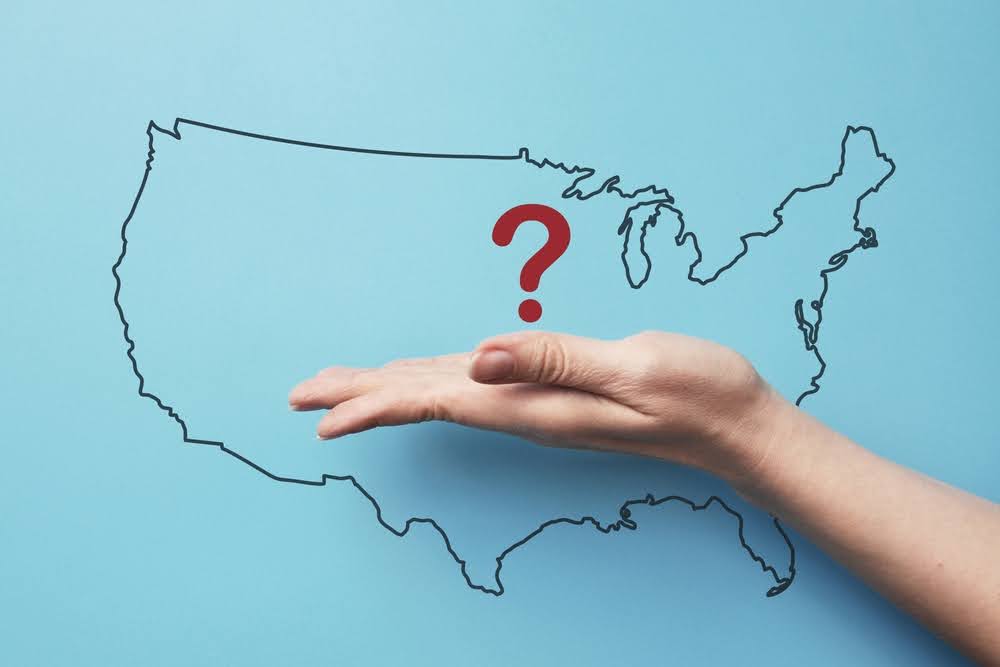outline map of the United States on a blue background with a hand in front and a question mark