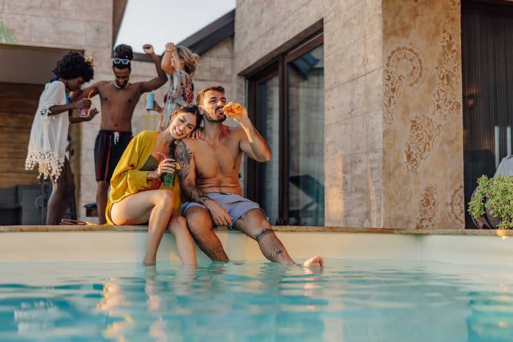 young group of friends enjoying beverages poolside