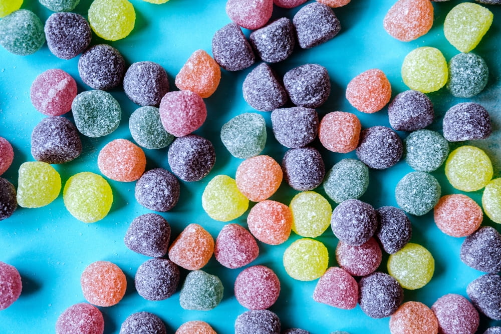 assortment of colorful, drop-shaped gummies on a blue countertop