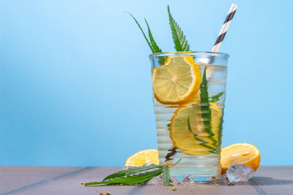 lemon infused, thc drink with a straw and ice against a blue backdrop
