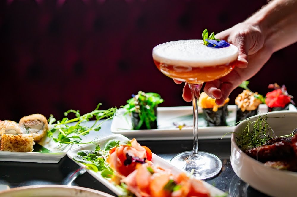 auburn drink in a margherita glass in the middle of a selection of appetizers