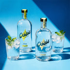 Two bottles of Herbal Oasis THC Mixer with two glasses filled with a clear liquid and ice on a blue background.